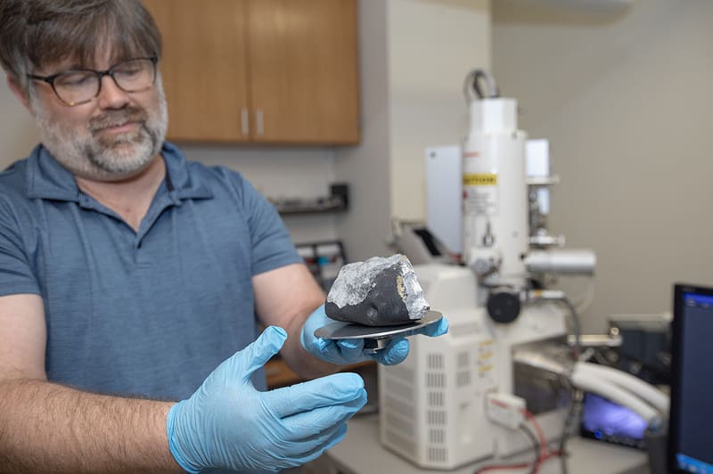 scientist holds up meteorite at TCNJ